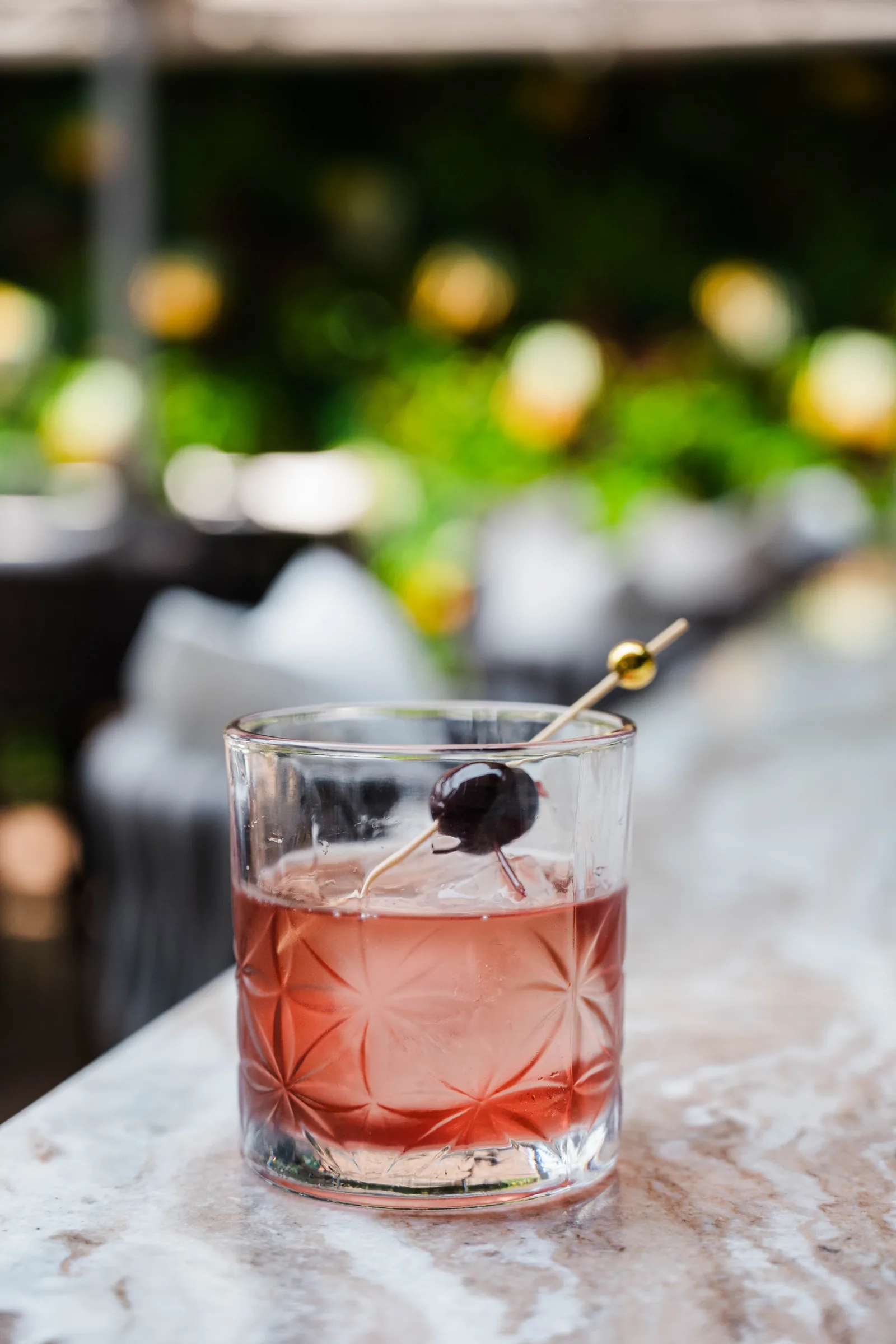 A cocktail with a brandied cherry on the marble bar