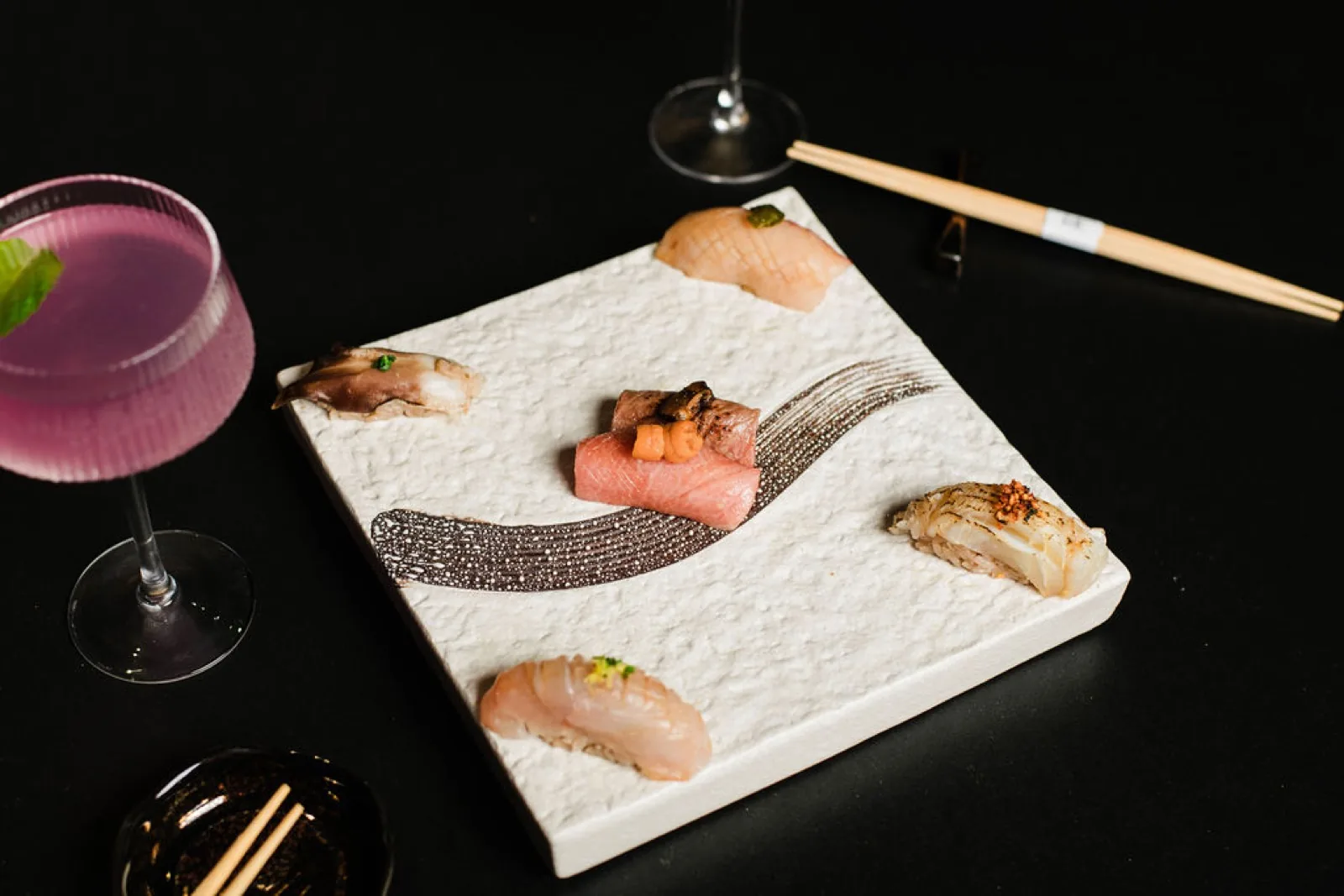 A nigiri board with cocktails at the omakase counter